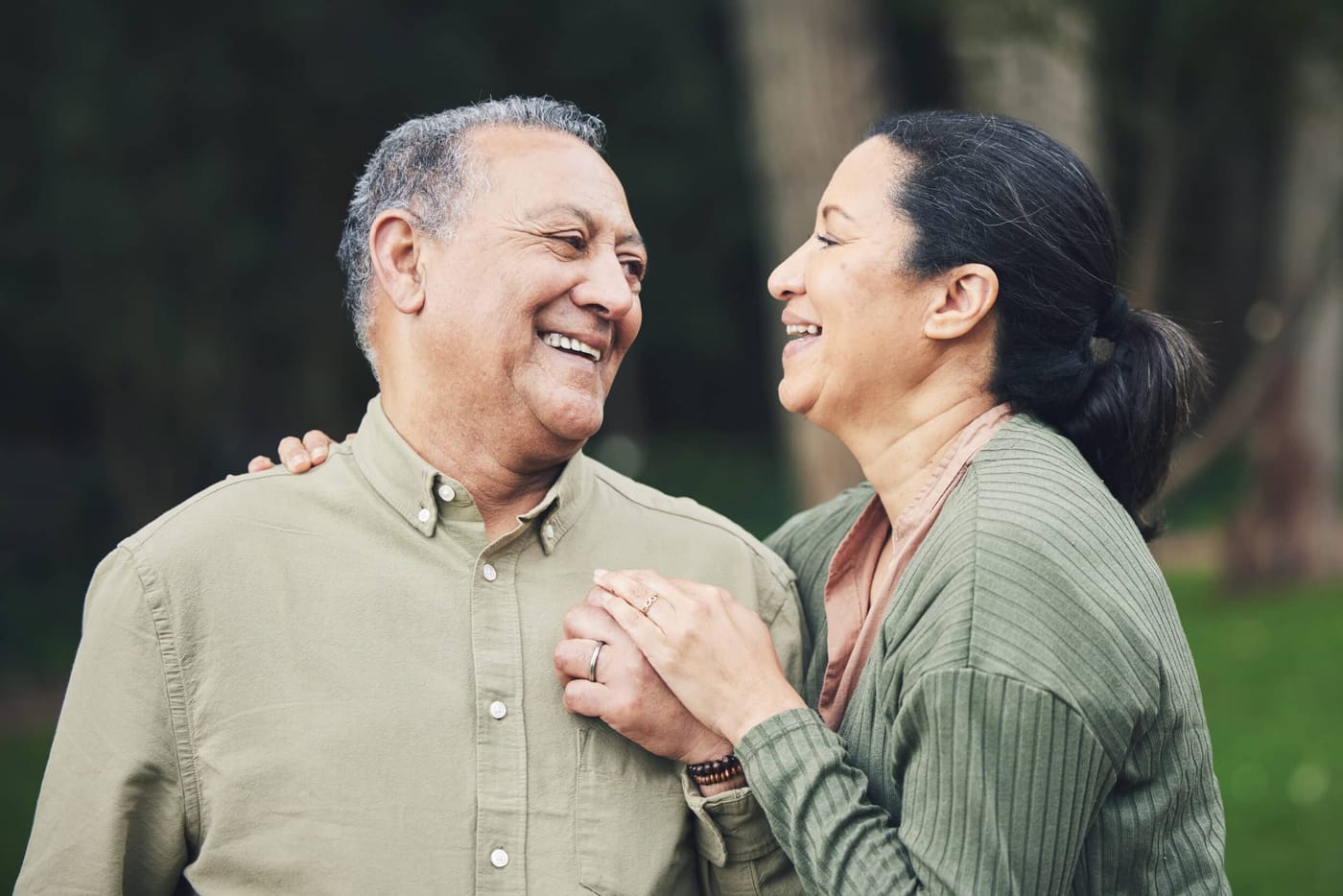 Una pareja mayor sonriente, muy juntos al aire libre