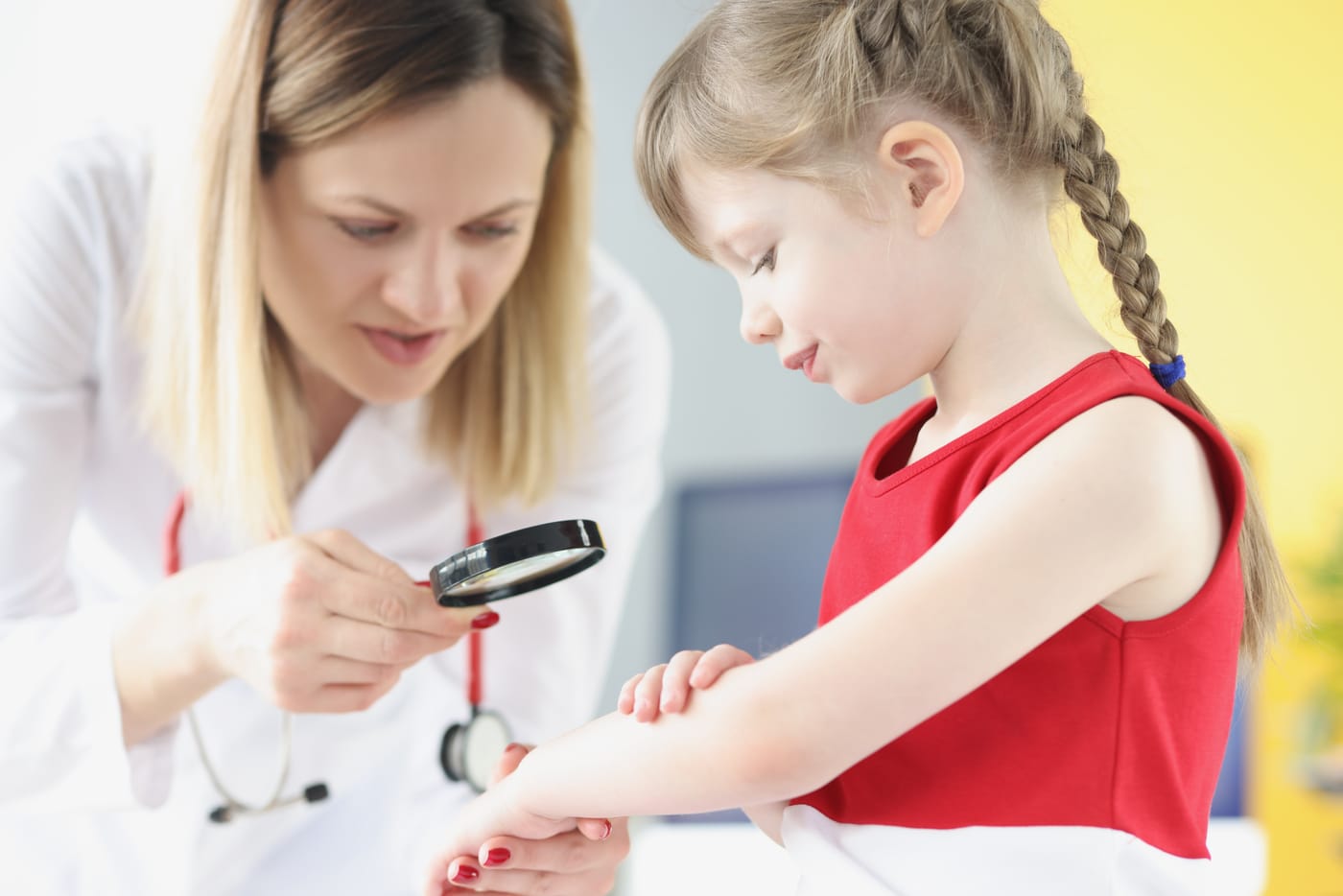 A doctor examines a rash on a little girl's arm with a magnifying glass