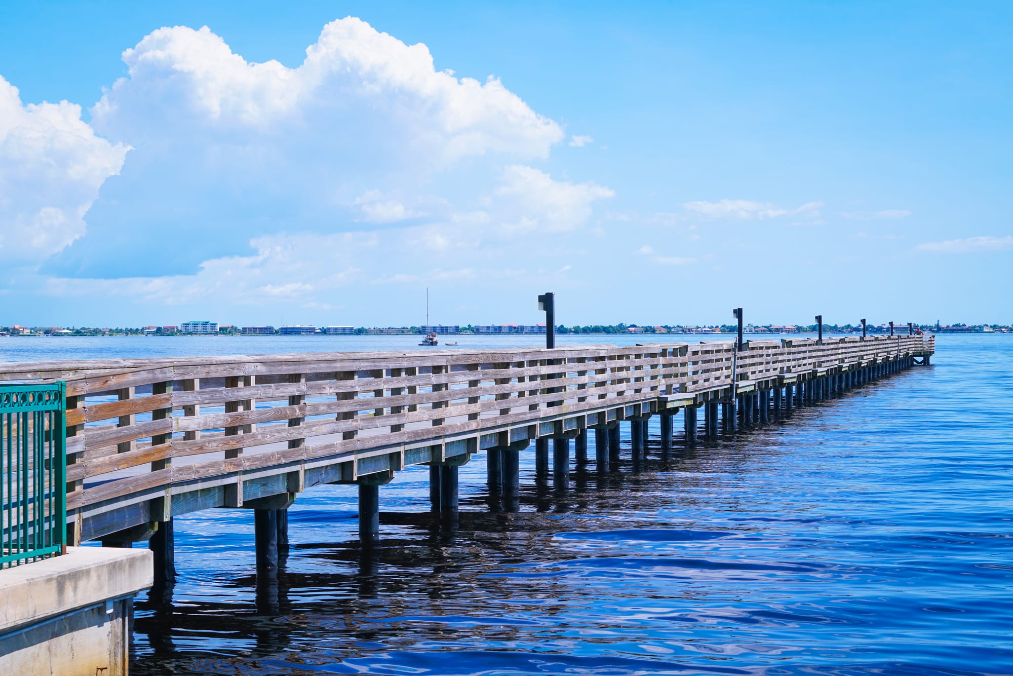 A fishing pier stretches into Charlotte Harbor under a bright blue sky