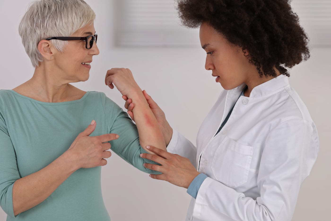 Examen dermatológico de una erupción roja e irritada en el antebrazo de una mujer mayor